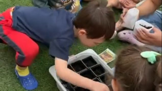 kids planting flowers on a small pot