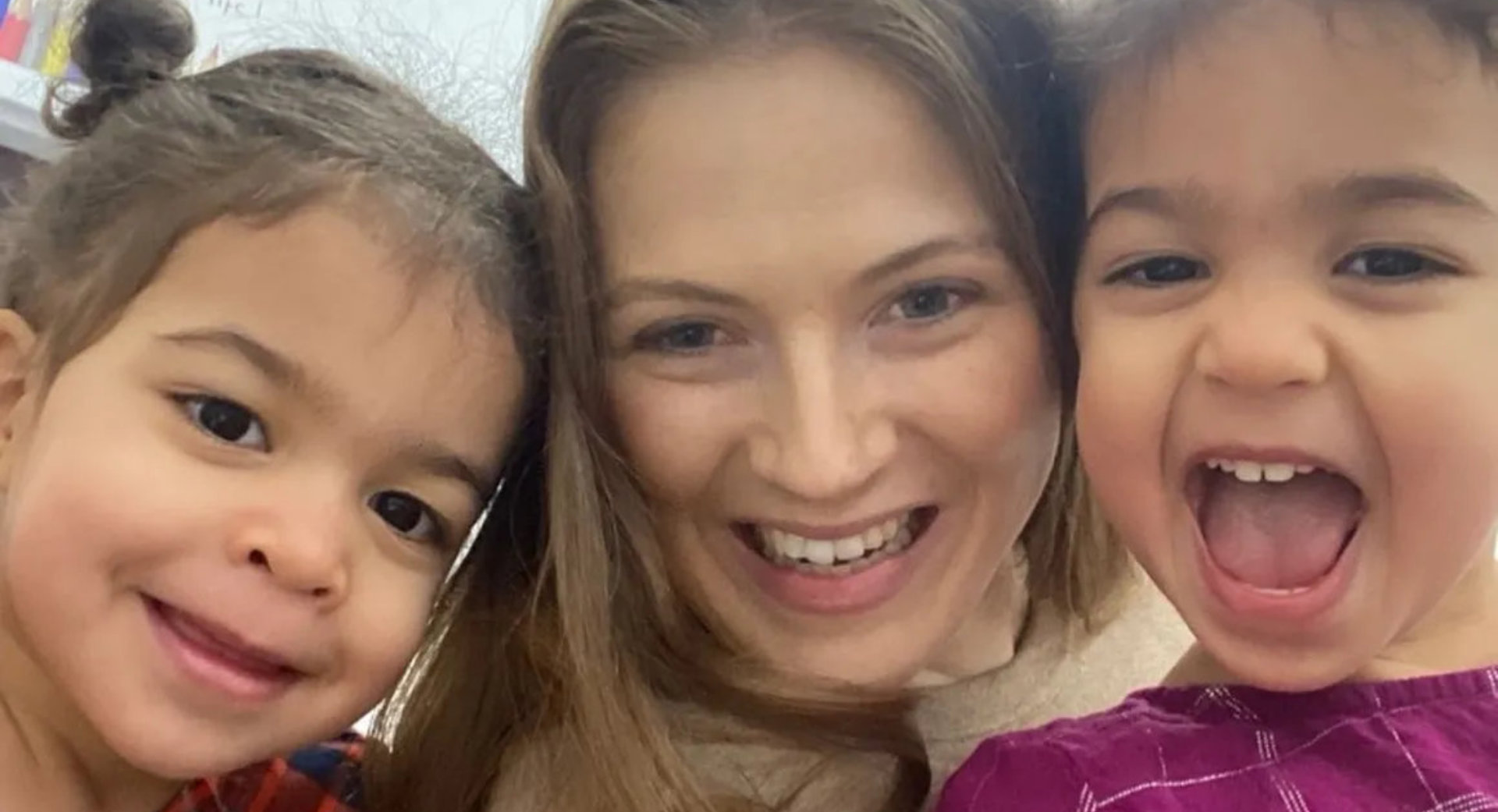 Smiling adult posing for a close-up selfie with two young children