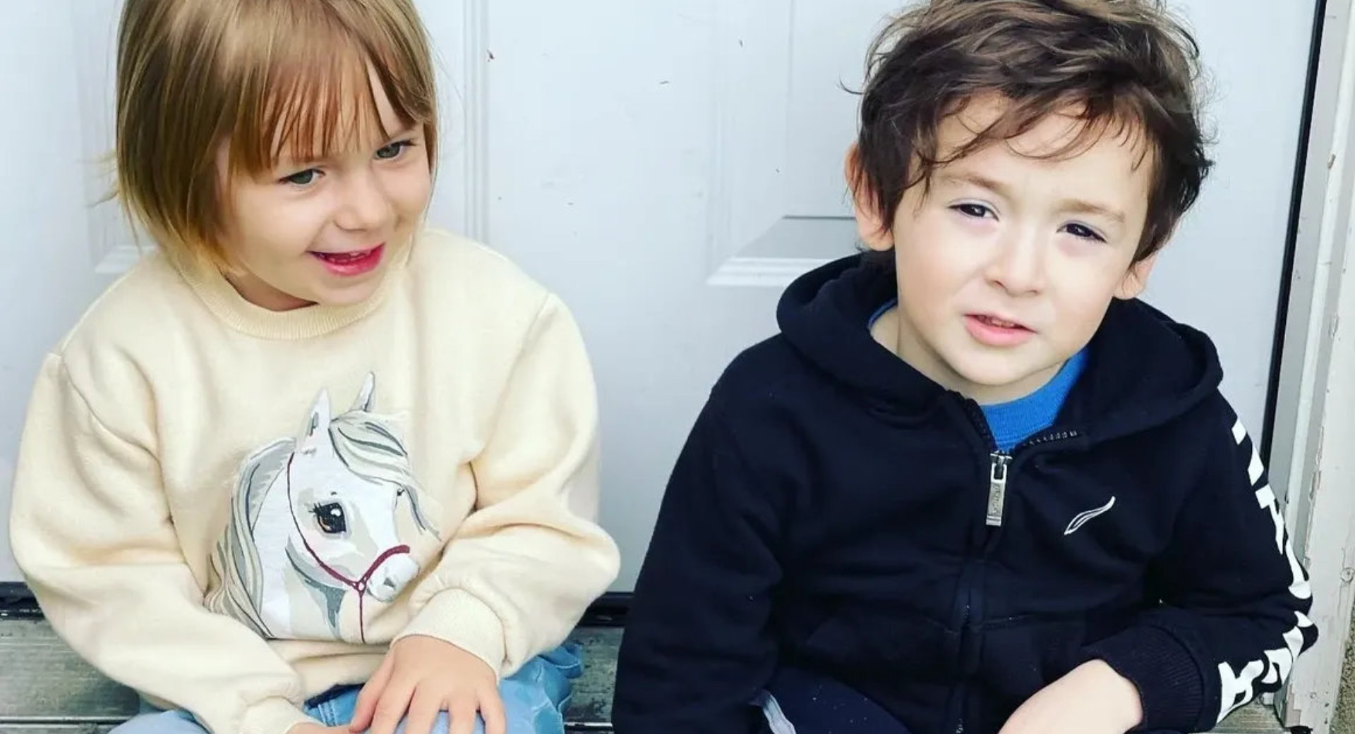 Two young children sitting together on a doorstep